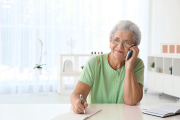 Sticker - Elderly woman speaking on cell phone at home