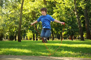 Wall Mural - Cute little boy jumping rope in park