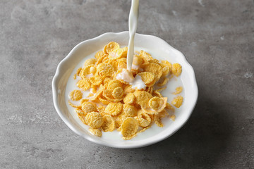 Wall Mural - Pouring milk into plate with cornflakes on table