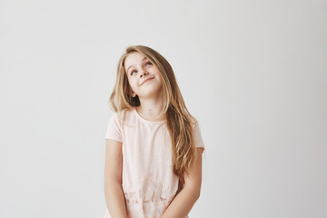 beautiful light-haired girl in pink dress looking upside with foxy face expression, thinking about l