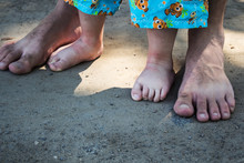 Male And Kid Feet Barefoot On The Ground