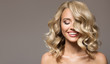 Leinwandbild Motiv Blonde woman with curly beautiful hair smiling on gray background.