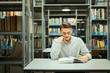 © Serhiy Hipskyy - Man sit on the library and read book with blur background