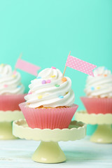 Tasty cupcakes on cake stand on green background