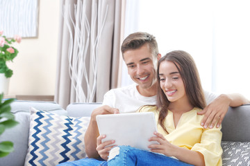 Canvas Print - Young couple using tablet computer on sofa at home