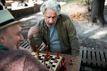 Mature male pensioner thinking about next move on chessboard