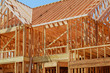 New residential construction home framing against a blue sky.
