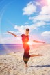 © raisondtre - Wonderful portrait of young elegant woman, dancing barefoot on the sand, on a background of blue sky and white clouds of air.