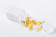 © DenisProduction.com - Yellow pills and white bottle. Vitamin pills and white plastic container, white background.