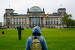 Young woman with backpack looking at Bundestag building in Berlin. Erasmus student, studying abroad and tourist concept.