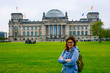 Young woman wearing glasses with backpack in front of the Bundestag building in Berlin. Erasmus student, studying abroad and tourist concept.