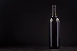 Fototapeta  - Bottle of red wine mock up on elegant dark black wooden background, copy space. Template for portfolio, advertising, design, branding identity, cover magazine, bar and restaurant menu.