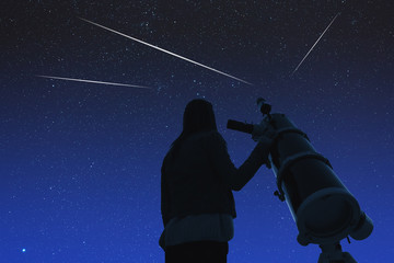 Wall Mural - girl looking at the stars through a telescope.