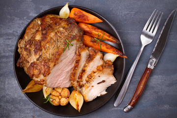 Wall Mural - Roasted sliced ham with vegetables and fork, knife on grey rustic background, view from above, top, horizontal