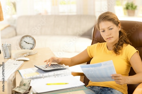Zdjęcie XXL Młoda kobieta kalkuluje koszty w domu