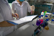 Asian female scientist writing down notes and test report from research with test tubes in laboratory, closeup.