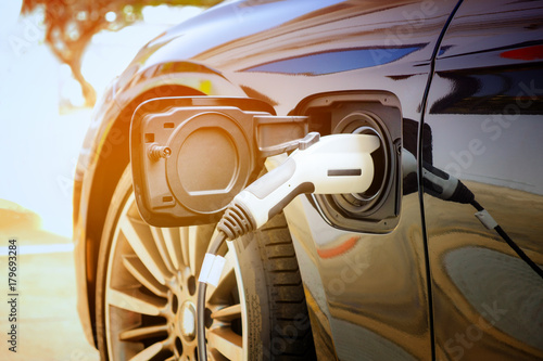 Fotografía Charging modern electric car battery on the street which are the future of the Automobile, Close up of power supply plugged into an electric car being charged for hybrid