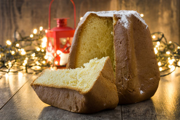 Pandoro Christmas cake with sugar and christmas light on wooden table