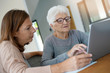 © goodluz - Elderly woman using laptop with help of homecarer