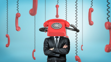 Wall Mural - a businessman with folded arms stands surrounded by phone receivers and with one red retro phone pla