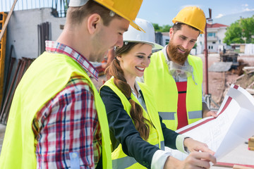 Confident female architect sharing ideas about the plan of a building under construction