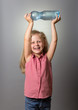 © laboko - Little smiling girl holds bottle of water over her head on gray