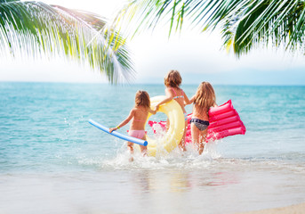 Wall Mural - Three girls running in the sea at tropical beach