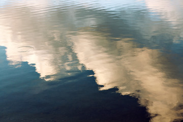 reflection of blue sky with white clouds in water, abstract background.