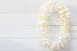 White Plumeria Flower lei garland flat lay on natural white pine wood background for Hawaii Lei day concept