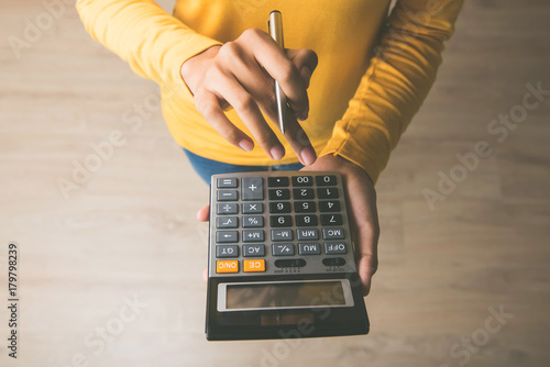 Cuadros en Lienzo Woman using a calculator with a pen in her hand
