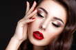 © demidenko - Beautiful woman portrait. Young lady posing close up on black background. Glamour make up, red lipstick, red nails.