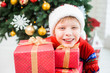 © Andrii Oleksiienko - Closeup portrait of excited cute little child in holiday christmas interior. Happy adorable kid posing with many presents in red wrapping paper. Horizontal color photography.