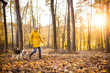© Halfpoint - Senior woman with dog on a walk in an autumn forest.