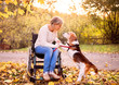 © Halfpoint - A senior woman in wheelchair with dog in autumn nature.