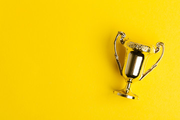 Gold winners achievement trophy on a yellow background