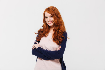 Wall Mural - Smiling pretty young redhead lady with arms crossed.