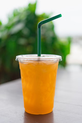 Orange juice  in a plastic glass placed on a wooden table.