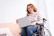 © Viacheslav Yakobchuk - Freelancing. Attractive alive blond handicapped woman smiling and using her laptop while sitting in the wheelchair