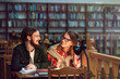 © proimagecontent - Portrait of two successful students casual stylish, boy and girl in library reading hall, evening time, education concept