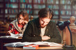 © proimagecontent - Portrait of two successful students casual stylish, boy and girl in library reading hall, evening time, education concept