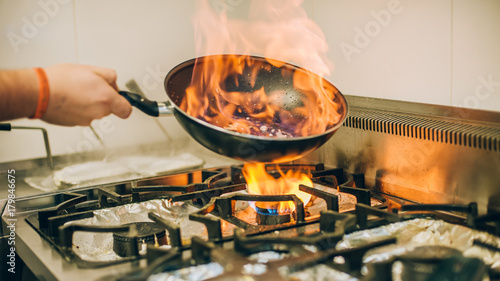 Zdjęcie XXL Kucharz gotuje posiłek w płomień ognia palić patelnię