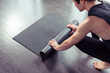 © uv_group - Yoga concept. Young men rolling mat after a yoga on black wooden floor