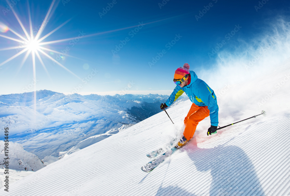 Skier skiing downhill in high mountains - obrazy, fototapety, plakaty 