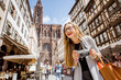 © rh2010 - Young woman tourist standing with photo camera in front of the main cathedral traveling in Strasbourg city in France