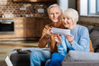 Happy couple. Positive nice aged couple sitting on the sofa and looking at the piece of paper while being in a good mood