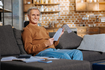 Wall Mural - Financial issues. Cheerful happy positive man smiling and reading a document while dealing with financial issues