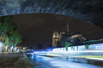 Wall Mural - Notre-Dame de Paris by night. Famous ancient catholic cathedral on the quay of the Seine river and city lights reflection. Touristic historical and architectural landmark. Tourism and travel concept.