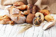 Assortment of baked bread and bread rolls on wooden table background.