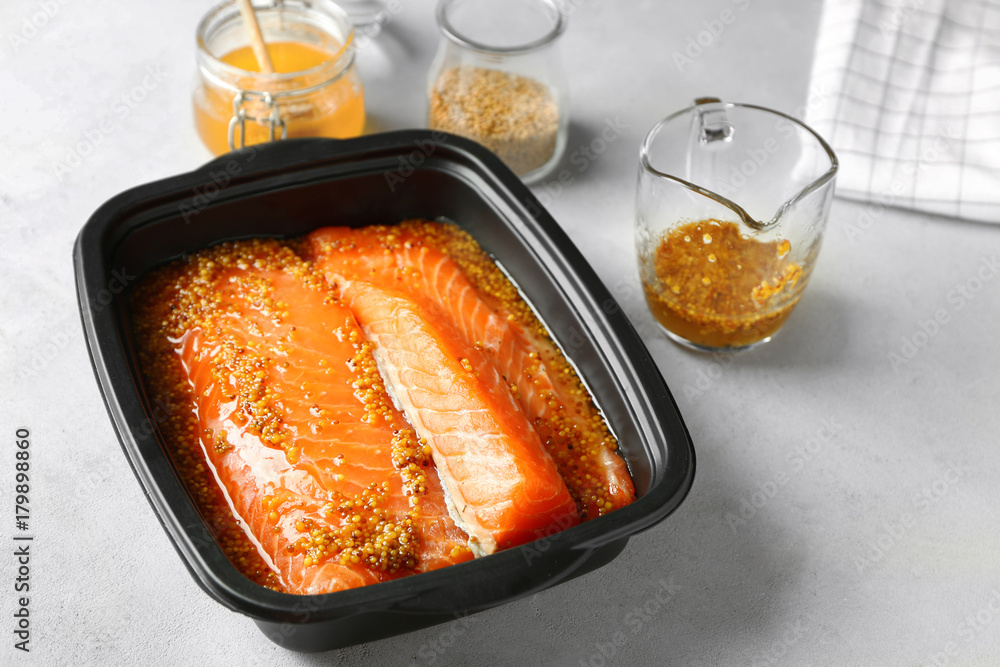 Dish with salmon fillet in honey mustard marinade on table