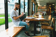 © JKstock - Pensive male blogger making work plan writing main points in notepad while sitting in a modern cafe. Relaxed hipster guy making notes while sitting at the table with a closed laptop on it.
